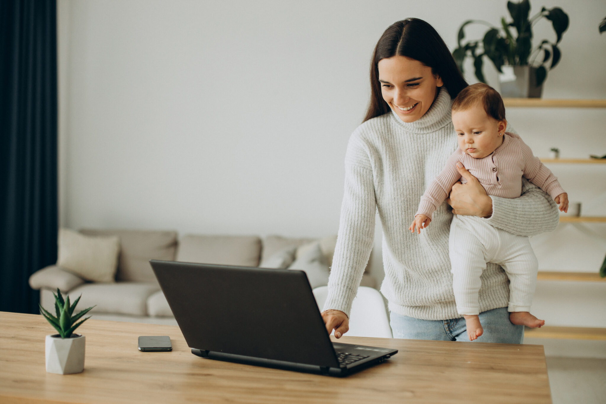 mother with baby daughter working computer from home