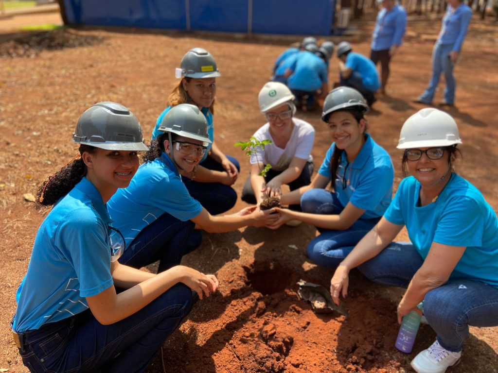 Jovens aprendizes com a coordenadora de Meio Ambiente, Lívia Reis, plantando árvores no bosque na usina CRV Industrial